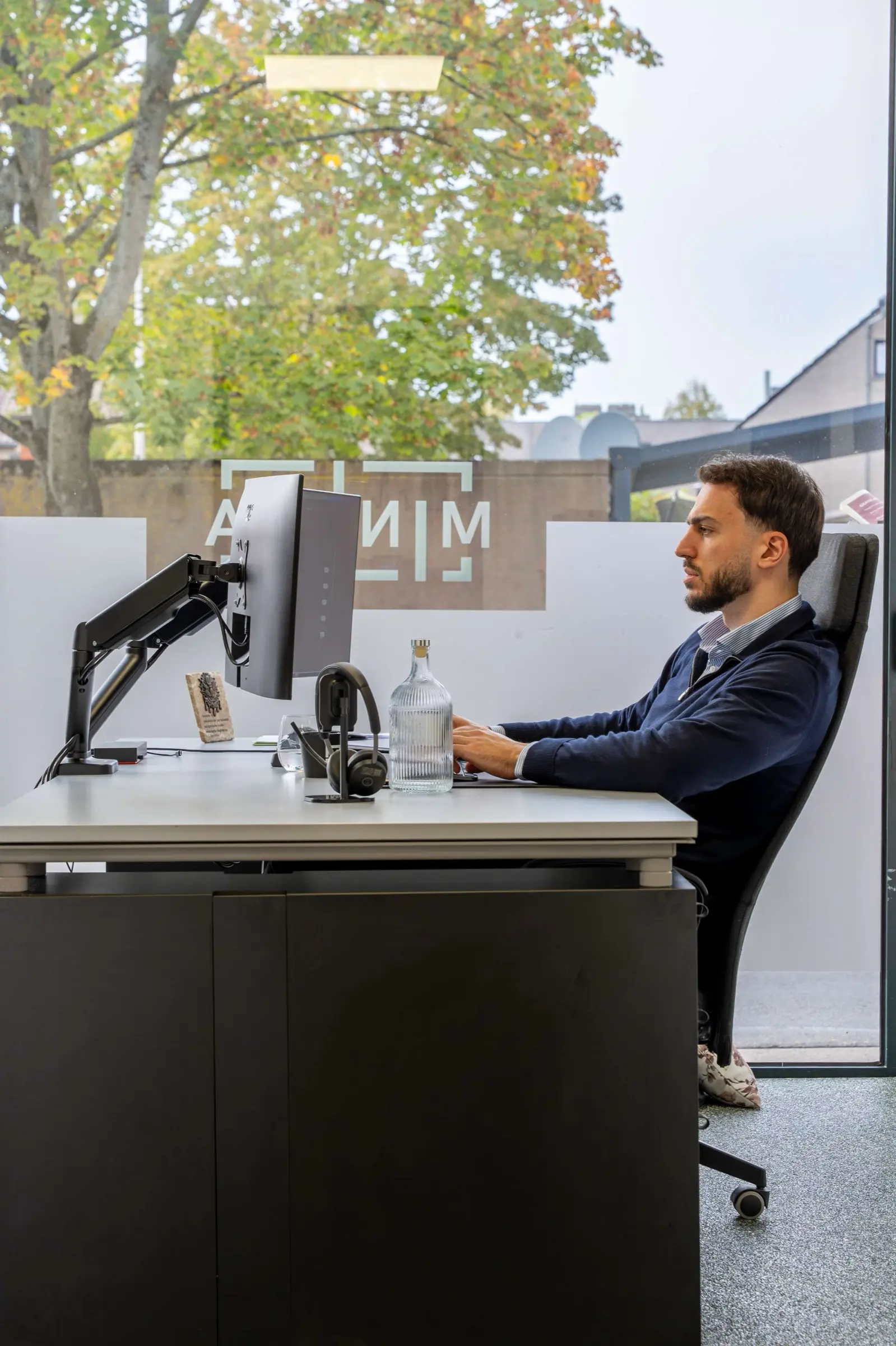 MINIMA-collega aan het werk aan het bureau bij het raam